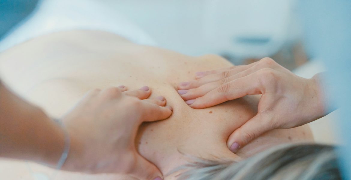 person massaging the back of a woman